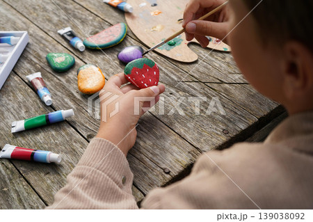 Boy paints strawberries on stones, carrots on pebbles making the most adorable stone fruit and veggie collection ever. Boy paints strawberries on stones, carrots on pebbles making the most adorable stone fruit and veggie collection ever. 139038092