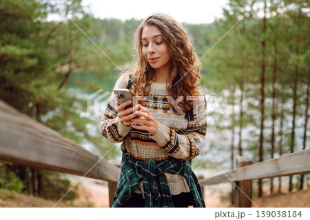 Portrait of a female traveler using her phone in the forest. Nice walk in the forest alone. Blogging Portrait of a female traveler using her phone in the forest. Nice walk in the forest alone. Blogging 139038184