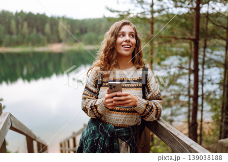 Portrait of a female traveler using her phone in the forest. Nice walk in the forest alone. Blogging Portrait of a female traveler using her phone in the forest. Nice walk in the forest alone. Blogging 139038188