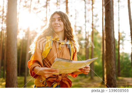 Young woman holding map in forest. Relaxed woman hiker looking navigation searching route. 139038503