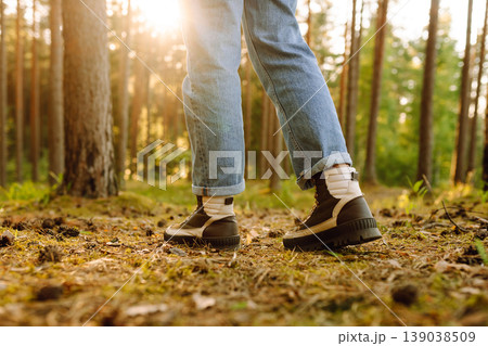 Hiker's boots stepping on a blanket of fallen autumnal orange leaves in the forest. Travel 139038509
