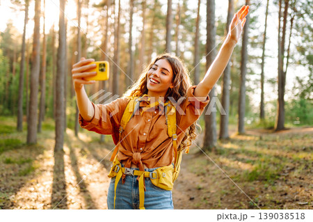 Selfie in nature. Beautiful woman taking picture of herself while walking in a sunny forest. Selfie in nature. Beautiful woman taking picture of herself while walking in a sunny forest. 139038518