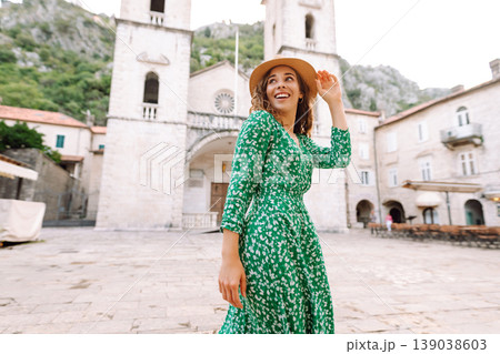Happy female tourist in beautiful dress walking in the street of the city. Fashion style. 139038603