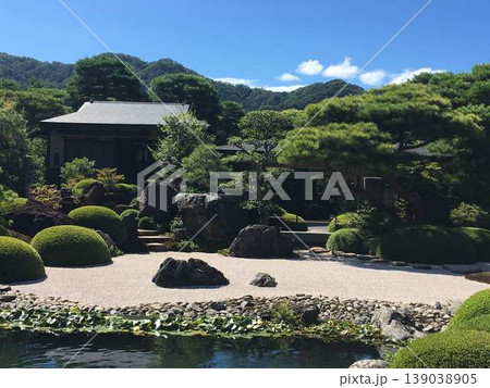 池泉回遊式庭園の全景、池と白砂に映える和風建築と山の借景が美しい日本の伝統的造園風景 池泉回遊式庭園の全景、池と白砂に映える和風建築と山の借景が美しい日本の伝統的造園風景 139038905
