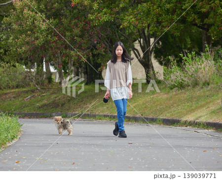 春の公園で可愛いポメラニアンの子犬を連れて散歩する女子中学生の姿 139039771