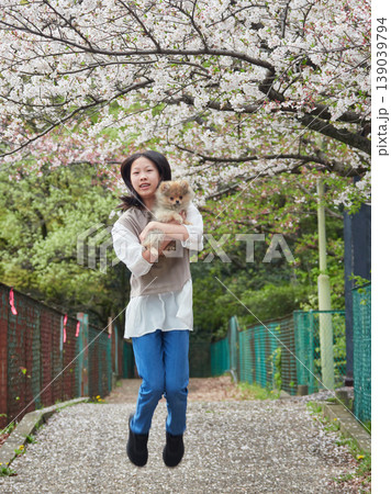 春の桜満開の公園で可愛いポメラニアンの子犬を連れて花見する女子中学生の姿 春の桜満開の公園で可愛いポメラニアンの子犬を連れて花見する女子中学生の姿 139039794