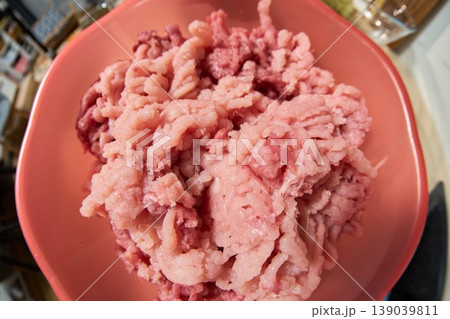 Macro ground pork in bowl ready for meal prep and mixing. Home cook scenario with warm lighting, ceramic bowl on countertop Macro ground pork in bowl ready for meal prep and mixing. Home cook scenario with warm lighting, ceramic bowl on countertop 139039811