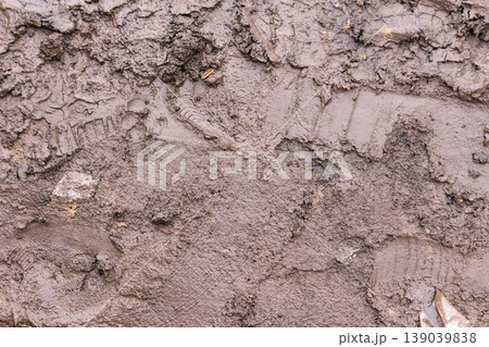 Wet muddy ground with tire tracks and footprints, illustrating bad road conditions Wet muddy ground with tire tracks and footprints, illustrating bad road conditions 139039838
