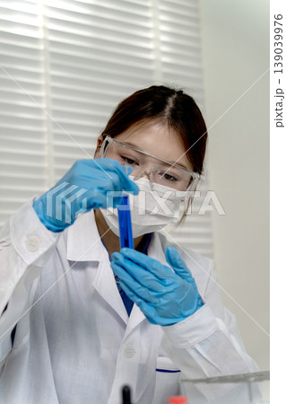 Asian adult scientist woman working lab examining blue test tube liquid for medical research and scientific discovery healthcare innovation development Asian adult scientist woman working lab examining blue test tube liquid for medical research and scientific discovery healthcare innovation development 139039976