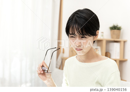 眼精疲労で目頭を押さえ、眼鏡を外して休息する日本人女性 眼精疲労で目頭を押さえ、眼鏡を外して休息する日本人女性 139040156