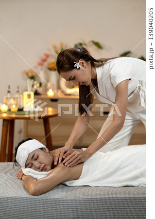Asian therapist performs hot stone massage on client back for deep relaxation holistic wellness treatment professional spa environment serene atmosphere self care body therapy Asian therapist performs hot stone massage on client back for deep relaxation holistic wellness treatment professional spa environment serene atmosphere self care body therapy 139040205