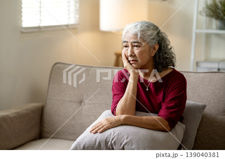 Asian senior woman deep thought alone home expressing sadness depression worry loneliness mental health problems 139040381