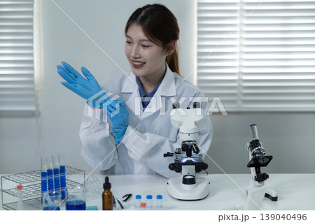 Asian adult woman scientist prepare laboratory work put on protective blue gloves for research experiment medical safety focus professionalism scientific discovery Asian adult woman scientist prepare laboratory work put on protective blue gloves for research experiment medical safety focus professionalism scientific discovery 139040496