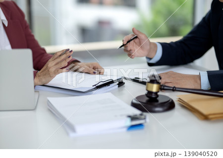 Legal professionals discuss important documents contract agreement case negotiation modern office setting justice gavel table Legal professionals discuss important documents contract agreement case negotiation modern office setting justice gavel table 139040520