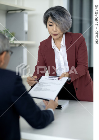 Adult Asian businesswoman presents criminal records document business transaction legal compliance corporate office professional setting 139040540