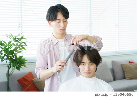 ヘアアイロンで髪をカールする若い日本人美容師 139040686