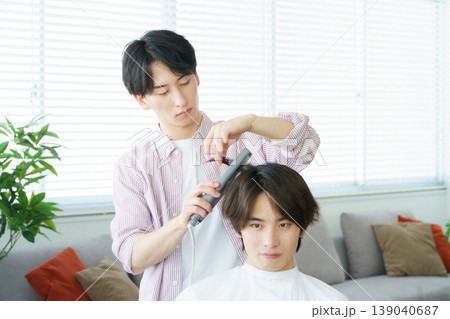 ヘアアイロンで髪をカールする若い日本人美容師 139040687