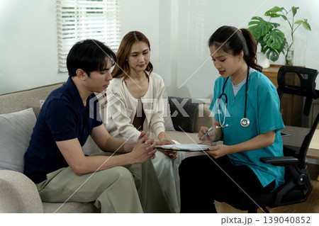 Healthcare professional consults Asian adult couple explaining health information home setting health advice providing medical guidance patient care well being discussion 139040852