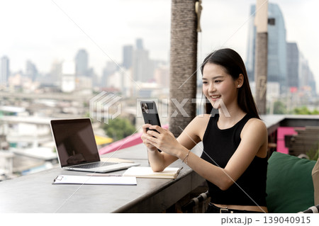 Asian adult woman uses smartphone rooftop cafe city view digital nomad online connection happy remote worker modern lifestyle global communication laptop use Asian adult woman uses smartphone rooftop cafe city view digital nomad online connection happy remote worker modern lifestyle global communication laptop use 139040915