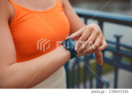 Woman Checking Smart Watch Before Running and Using Wireless Earbud. Fitness. Woman Checking Smart Watch Before Running and Using Wireless Earbud. Fitness. 139041591
