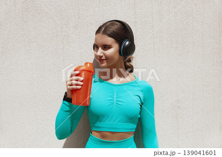Beautiful fitness athlete woman drinking water after work out exercising. Woman drinking water from bottle. Female drinking water after exercises or sport Beautiful fitness athlete woman drinking water after work out exercising. Woman drinking water from bottle. Female drinking water after exercises or sport 139041601