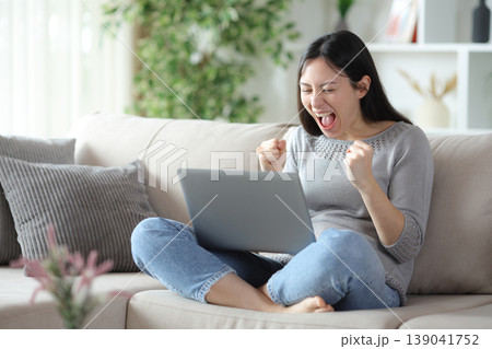 Excited asian woman celebrating checking computer Excited asian woman celebrating checking computer 139041752