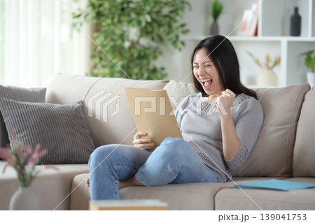 Excited asian woman checking paper documents Excited asian woman checking paper documents 139041753