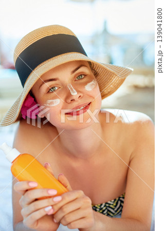 Skincare. Beauty Concept. Young pretty woman holding sun cream and applying on her face. Female in hat smear sunscreen lotion on skin and touch own face. Skin Protection and dermatology. Skincare. Beauty Concept. Young pretty woman holding sun cream and applying on her face. Female in hat smear sunscreen lotion on skin and touch own face. Skin Protection and dermatology. 139041800