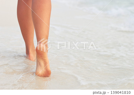 Woman walking on sand beach leaving footprints in the sand. 139041810