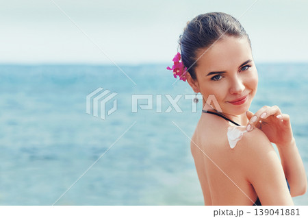 Woman applying sunscreen creme on tanned shoulder. Skincare. Body Sun protection sun cream. Bikini woman smear moisturizing lotion on back. Woman applying sunscreen creme on tanned shoulder. Skincare. Body Sun protection sun cream. Bikini woman smear moisturizing lotion on back. 139041881