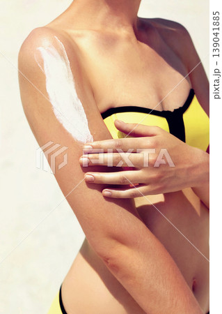Young woman with sun cream on the shoulder relaxing on the beach Young woman with sun cream on the shoulder relaxing on the beach 139041885
