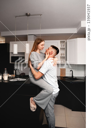 Couple shares a moment in the kitchen, one partner lifts the other while smiling and enjoying time together 139041937