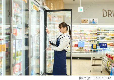 冷蔵庫の在庫を確認する女性店員 冷蔵庫の在庫を確認する女性店員 139042042