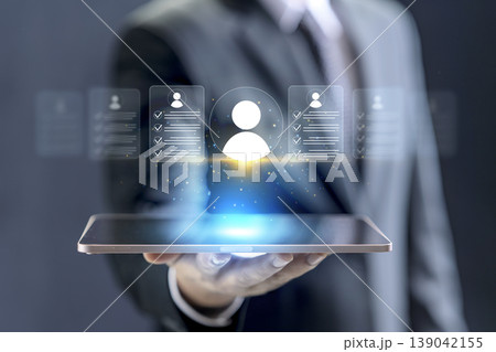Businessman holding a tablet with holographic user profiles and resumes for digital recruitment, human resources management, and talent selection 139042155