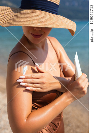 Beautiful Woman Applying Sunscreen On Shoulder At Beach With Hat. Beauty Skincare Concept. Female Using Sun Cream For Skin Protection Beautiful Woman Applying Sunscreen On Shoulder At Beach With Hat. Beauty Skincare Concept. Female Using Sun Cream For Skin Protection 139042712