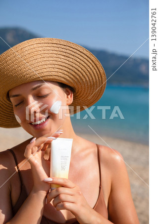 Pretty Woman Applying Sunscreen On Face With Closed Eyes At Beach. Beauty Skincare Concept. Female Using Sun Cream Lotion For UV Protection Pretty Woman Applying Sunscreen On Face With Closed Eyes At Beach. Beauty Skincare Concept. Female Using Sun Cream Lotion For UV Protection 139042761