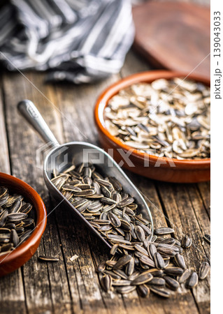 Sunflower Seeds in Metal Scoop on Rustic Wooden Table With Ceramic Bowls for Snacking and Cooking 139043033