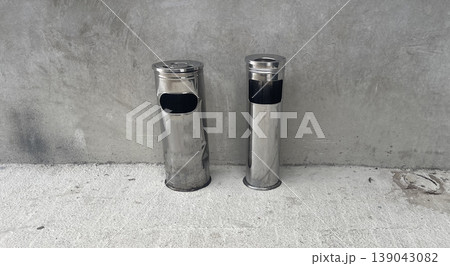 Trash and recycling bins stand side by side on a concrete surface in an urban area during the day 139043082