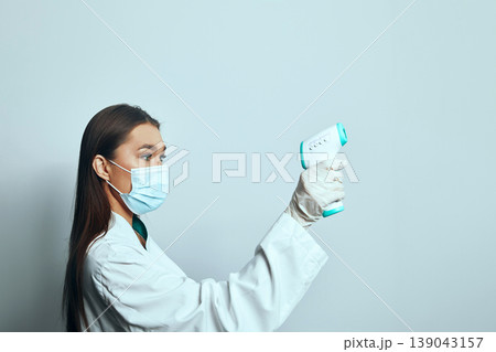 Health worker checks temperature of patient using a digital thermometer in a bright room with simple walls during a health examination Health worker checks temperature of patient using a digital thermometer in a bright room with simple walls during a health examination 139043157