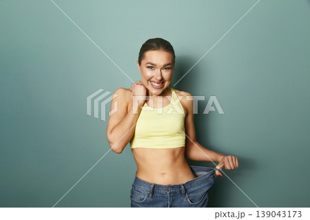 Woman shows off new outfit with joy in a studio against a plain background during daylight hours 139043173