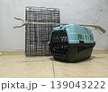 Pet carrier and metal crate placed on tiled floor in a room during evening hours 139043222