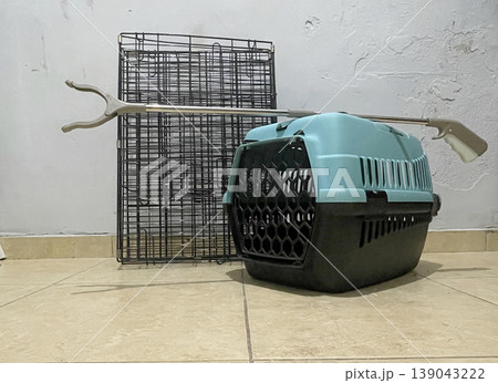 Pet carrier and metal crate placed on tiled floor in a room during evening hours Pet carrier and metal crate placed on tiled floor in a room during evening hours 139043222