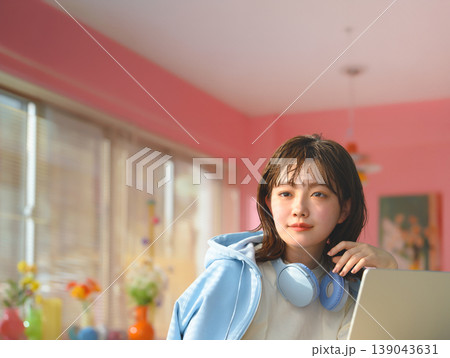 女性がヘッドホンを首にかけてノートパソコンを使う ：はっぴぃぽっぷ 139043631