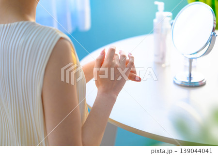 鏡の前でハンドケアをする女性 ：はっぴぃぽっぷ 139044041