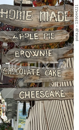 Wooden signs advertising homemade desserts including apple pie and cheesecake outside a shop Wooden signs advertising homemade desserts including apple pie and cheesecake outside a shop 139044221