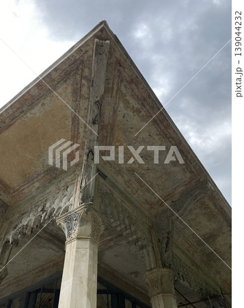 Architectural detail of ornate ancient column and ceiling with cloudy sky background Architectural detail of ornate ancient column and ceiling with cloudy sky background 139044232