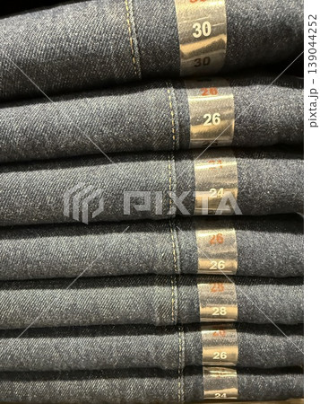 Folded denim jeans in various sizes on display in retail store as clothing background Folded denim jeans in various sizes on display in retail store as clothing background 139044252