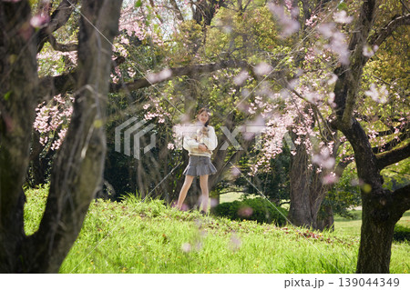 春の桜満開の公園で可愛いポメラニアンの子犬を連れて花見する女子中学生の姿 春の桜満開の公園で可愛いポメラニアンの子犬を連れて花見する女子中学生の姿 139044349
