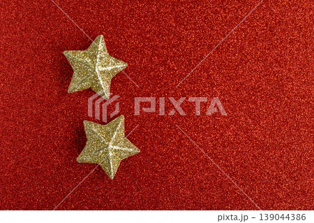 Golden sparkling stars on a red glittering background. Golden sparkling stars on a red glittering background. 139044386