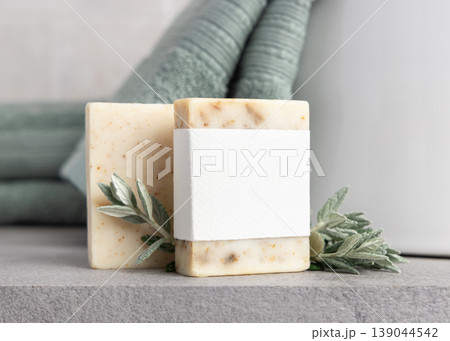 Beige solid soap bars with blank paper label mockup near with leaves and sage green bath towel Beige solid soap bars with blank paper label mockup near with leaves and sage green bath towel 139044542